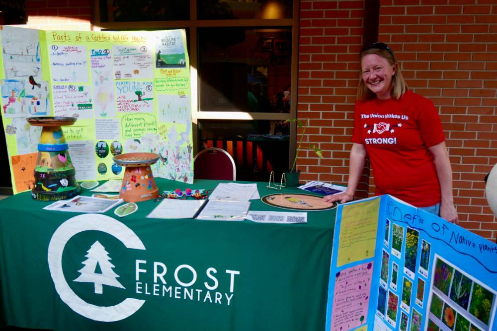CA Frost Elementary teacher poses by their table featuring native plant information